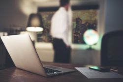 Laptop and paper with business man in background