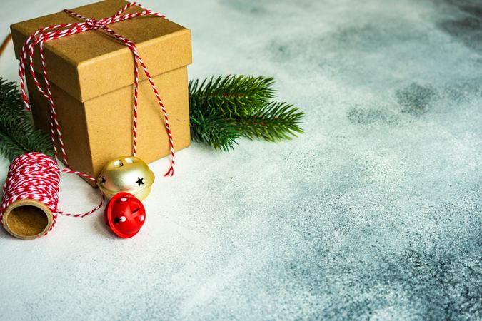 Christmas gift wrapped in red striped string with pine and bells