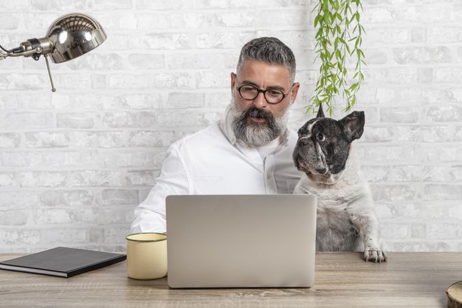Man working from home with his bulldog sitting together in office
