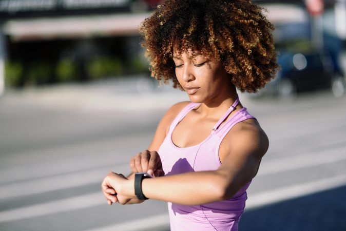 Female with afro hair looking at her smart watch during workout