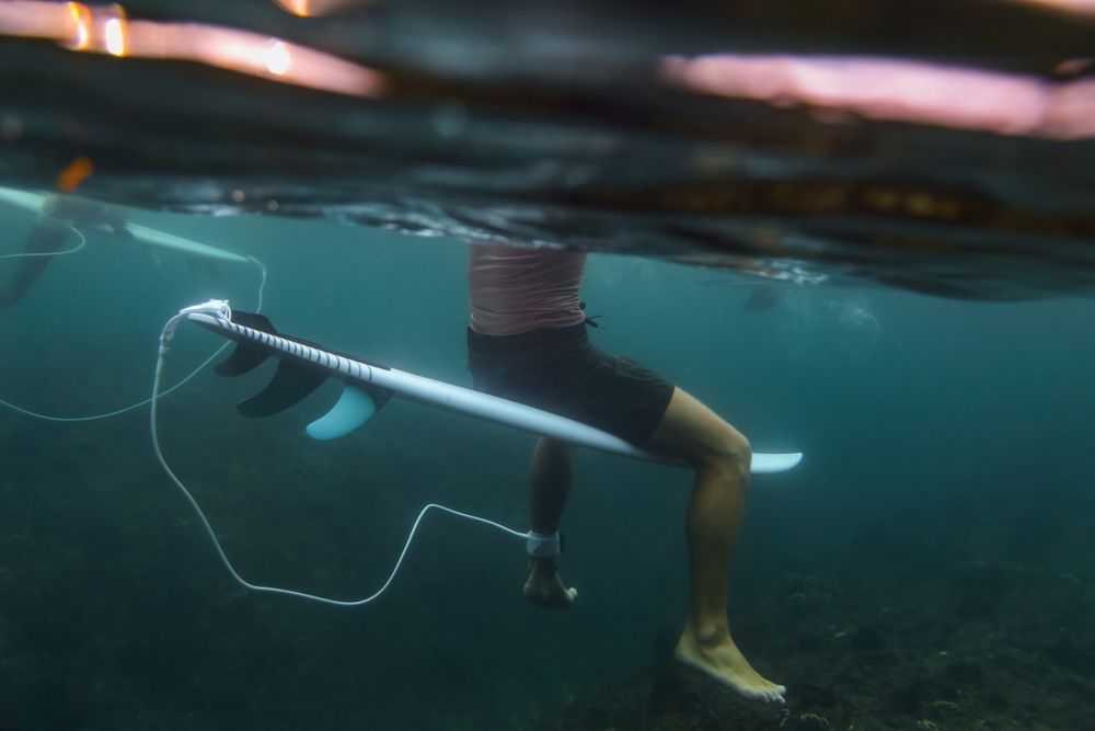 Man sitting on surf board floating in blue water