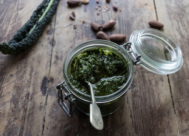 Jar with kale pesto near nuts