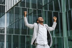 Enthusiastic Black man rejoicing raising hands up