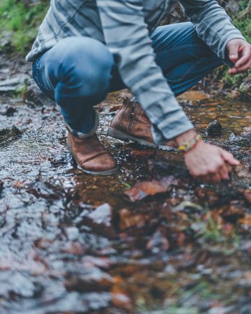 Man squatting on forest trail
