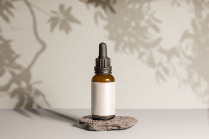 Mockup of a cosmetic product bottle, isolated, with the label in white and flat plants shadows