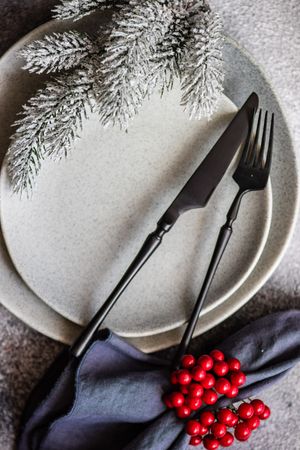 Christmas table setting with snowy pine branch and holly