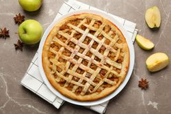 Composition with apple pie and ingredients on gray background, top view