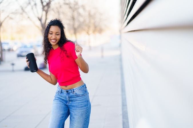 A Joyful Young Woman Dancing Exuberantly Outdoors While Holding a Cup of Coffee in Her Hand