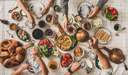 Group of people having Turkish style fresh breakfast with eggs, breads, vegetables