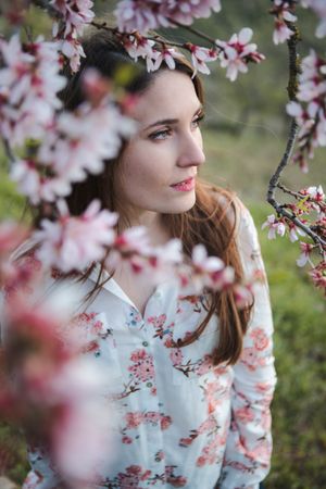 Young happy woman between trees in garden