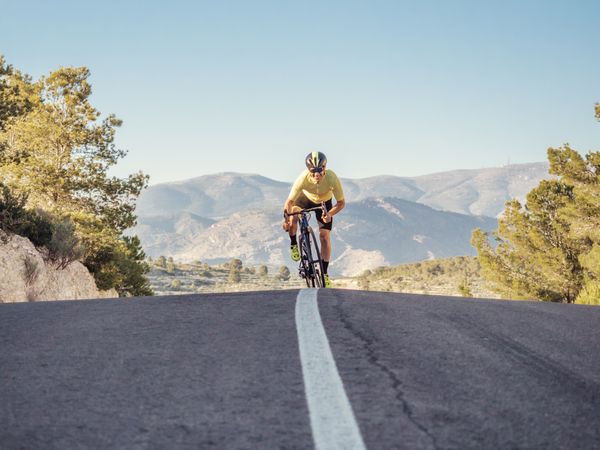healthy man riding a bicycle on a mountain road in a sunny day