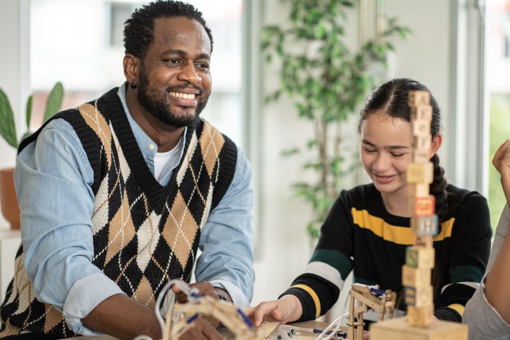 Happy male teacher working with wooden blocks in his classroom