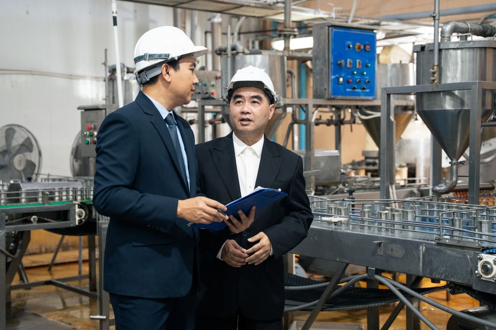 A businessman inspecting canned fish on conveyor belt at the factory