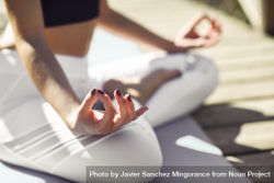 Close up of woman wearing sport clothes meditating on yoga mat on forest path 0v2zd0