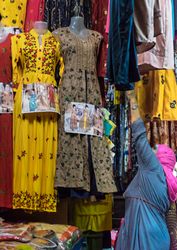 Woman in a pink headscarf at a market with patterned clothes