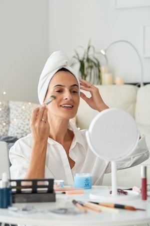 Cheerful female applying makeup in morning