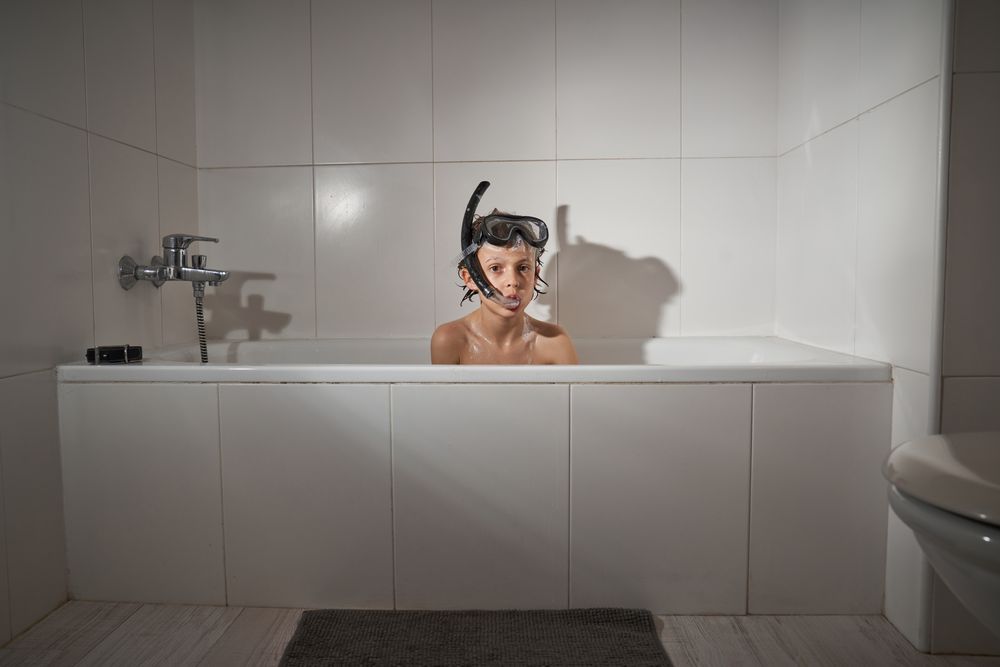 Boy in snorkeling mask sitting in bathtub