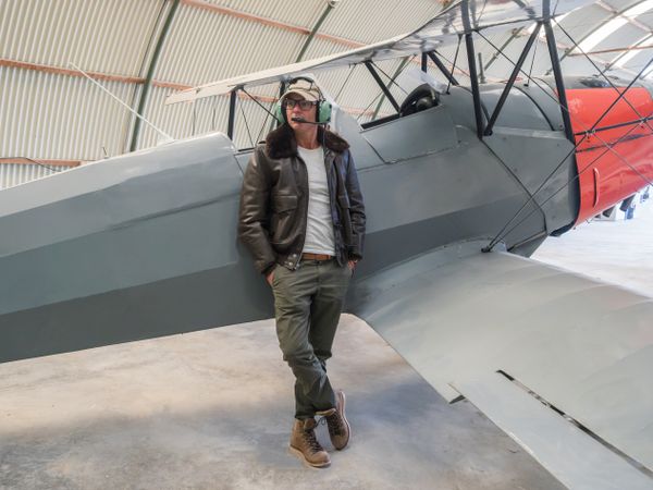 Confident pilot beside retro plane in hangar