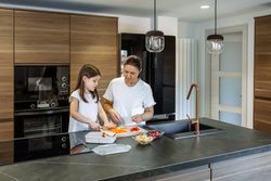 Mother teaching her daughter to cut vegetables for lunch box