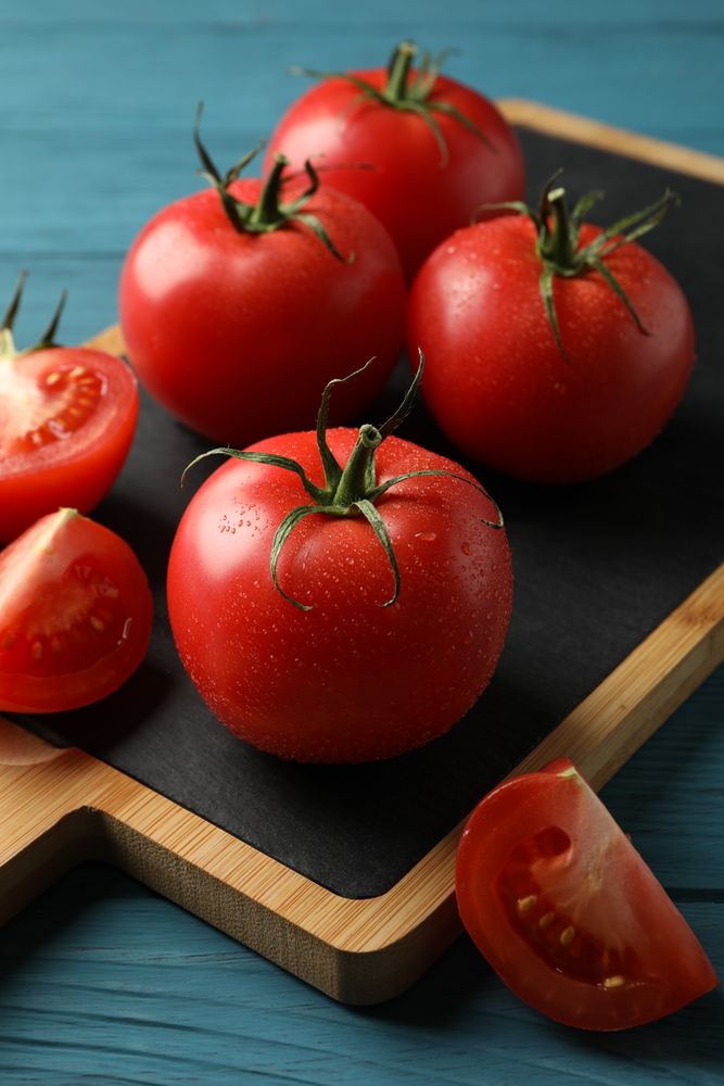 Fresh tomatoes on board on wooden table. Ripe vegetable