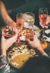 Group of people at festive fall dinner toasting with wine in different glassware over pie