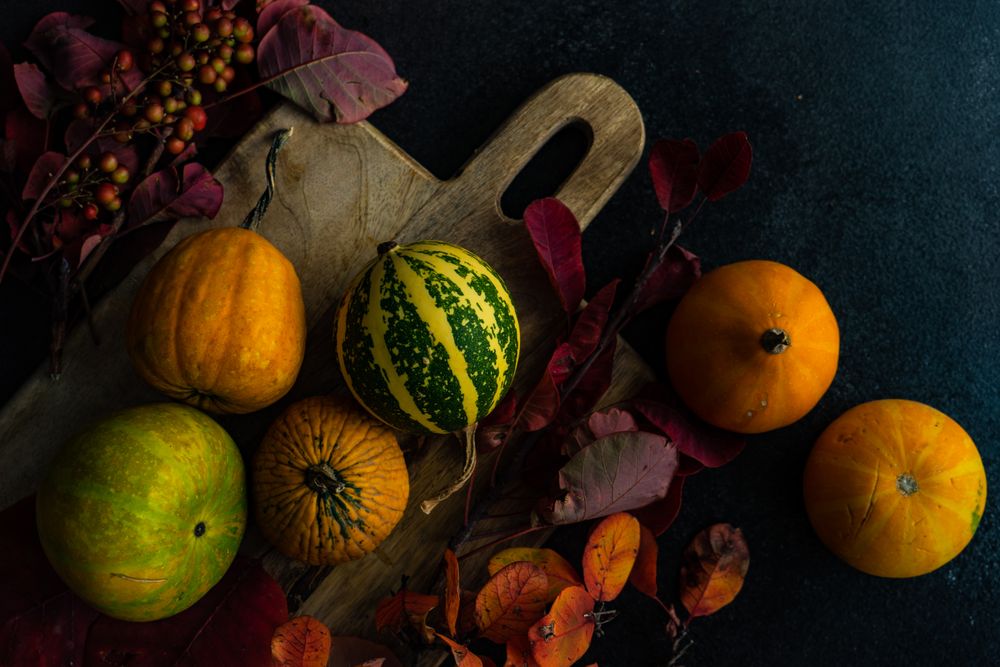 Top view of autumn squash on rustic breadboard and leaves