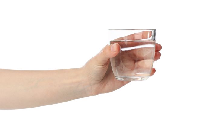 Hand holding glass of water in studio shoot