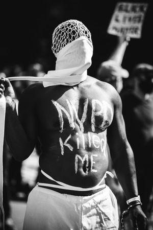 Grayscale photo of man with text "NYPD killed me" painted on his chest during Black Lives Matter protests