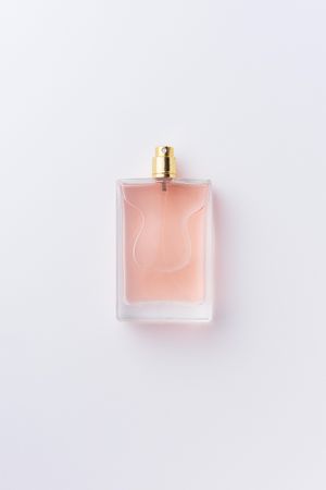 Pink perfume over pale background