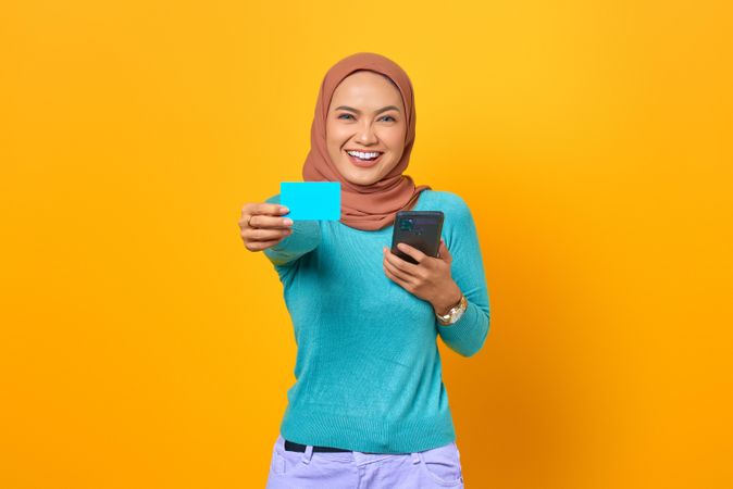 Muslim woman looking happy with credit card forward and smartphone