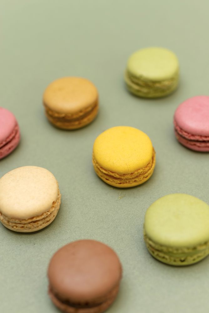 Rows of nine macaroons on green table from above