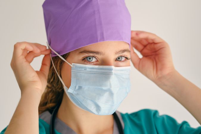 Woman putting on mask and looking at camera