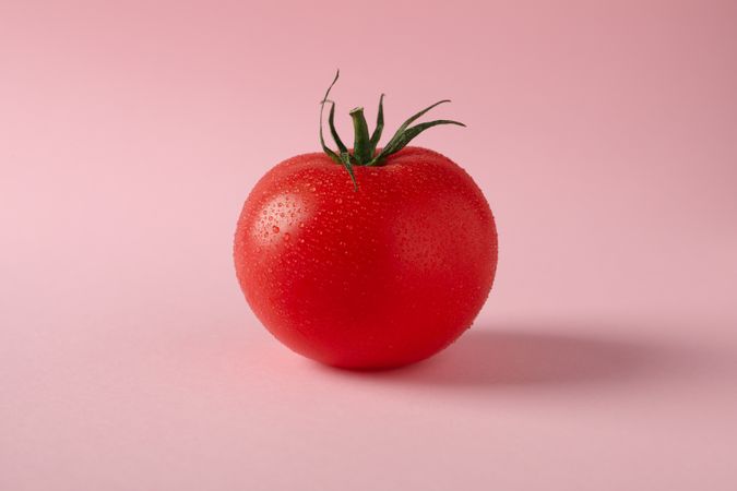 Fresh ripe tomato on pink background, close up