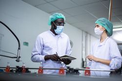 Two colleagues working at conveyor belt at drink factory