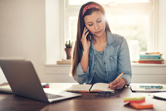 Woman taking notes while on a phone call