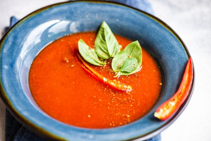 Traditional Spanish soup of tomato gazpacho with basil garnish in blue bowl