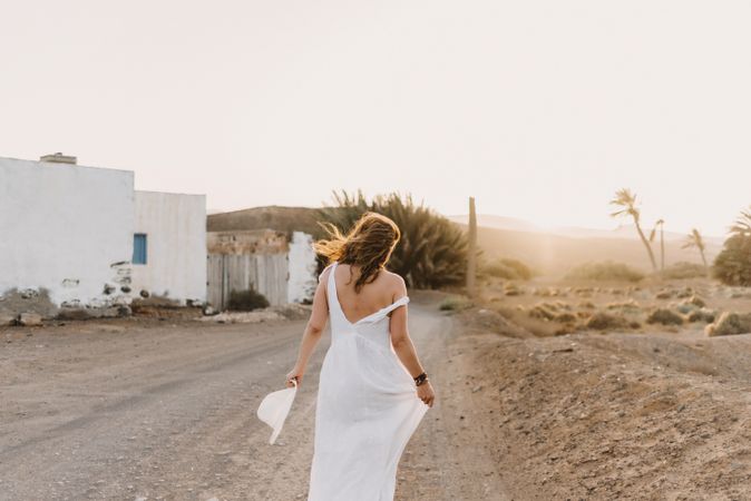 Woman in white dress in dry field in sunlight