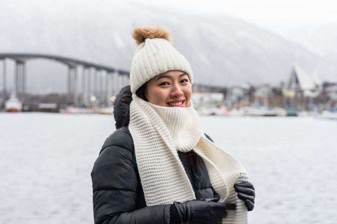Asian female tourist in warm wear at snowy field near city