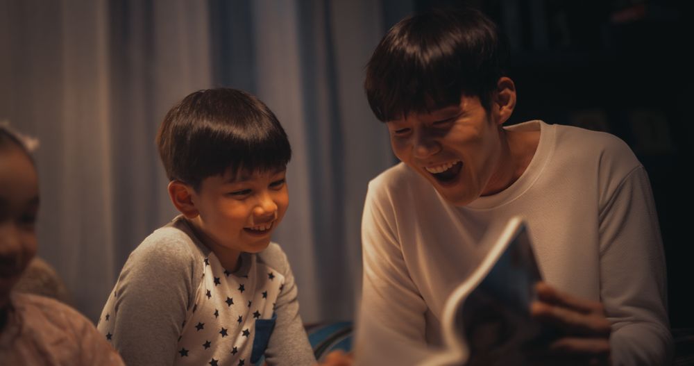 Patient Father Helping his Children to Learn how to Read Their Favorite Book.