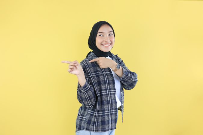 Portrait of Smiling Young Asian Indonesian Woman Pointing Finger
