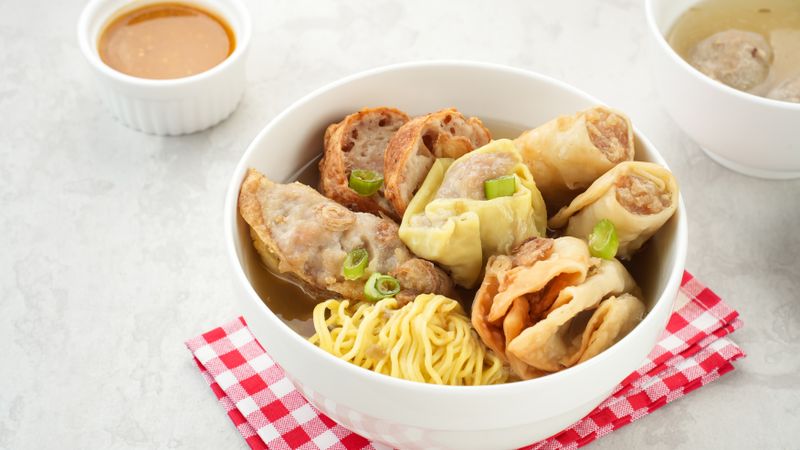 Bakso Malang, meatball soup with tofu, fried shumay, noodles and dumplings. Served with sambal and cucumber