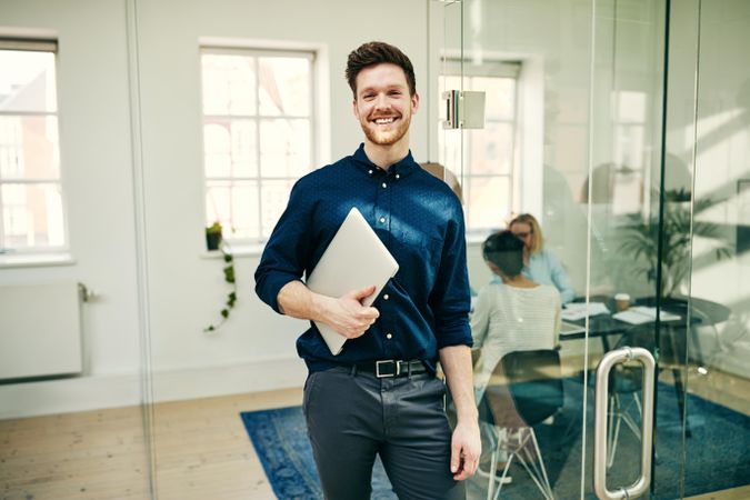 Portrait of smiling businessman holding laptop in the office