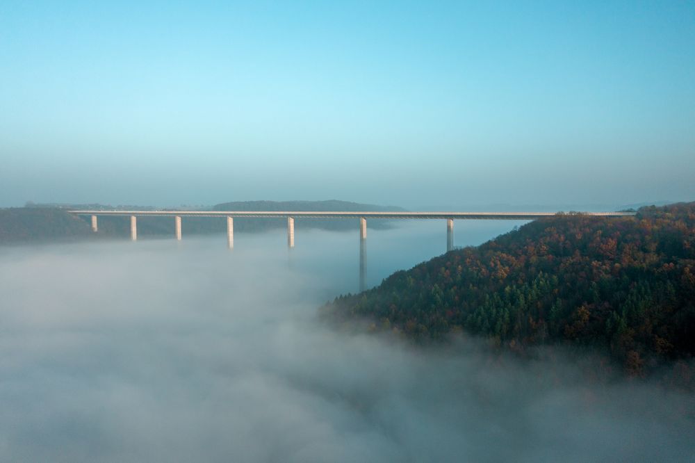 Highway bridge over dense fog, drone aerial view, at sunrise in Germany