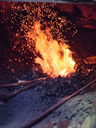 Unrecognizable blacksmith burning metal in furnace
