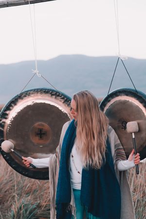 Woman near ethnic gongs on field