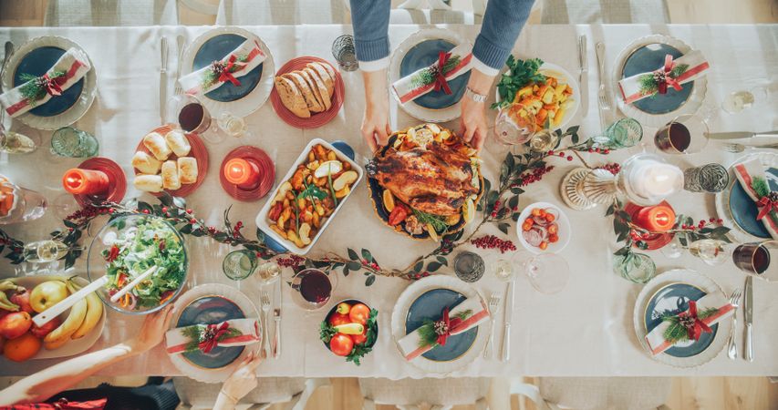 Top Down View Establishing Shot with Elegant Christmas Table with a Roast Turkey, Carefully Arranged Garnishes, Baked Potatoes, Variety of Vegetables, Decorative Elements and Candlelights
