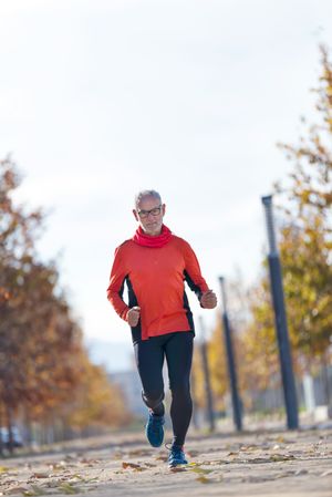 Front of fit grey haired male running outside