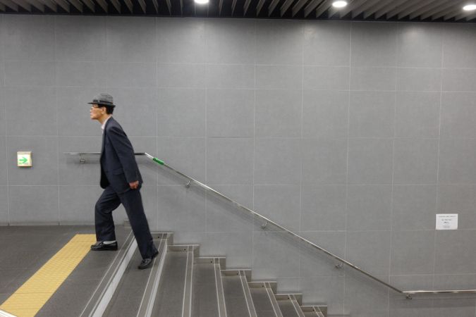 Side view of man in suit and fedora hat climbing staircase