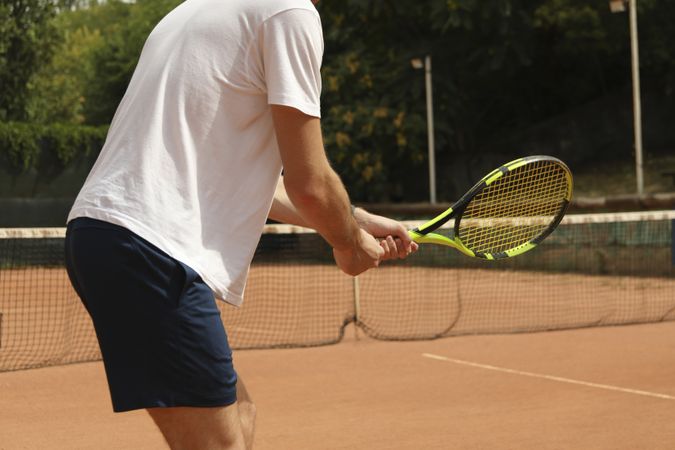 Young man playing tennis on clay court