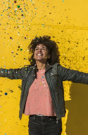 Black woman with afro hair celebrating with confetti.